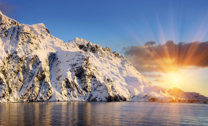 De schijnende zon die tussen de ijzige rotsen doorkomt